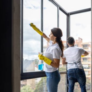 Team of professional Latin American cleaners cleaning the windows of an apartment - housework concepts